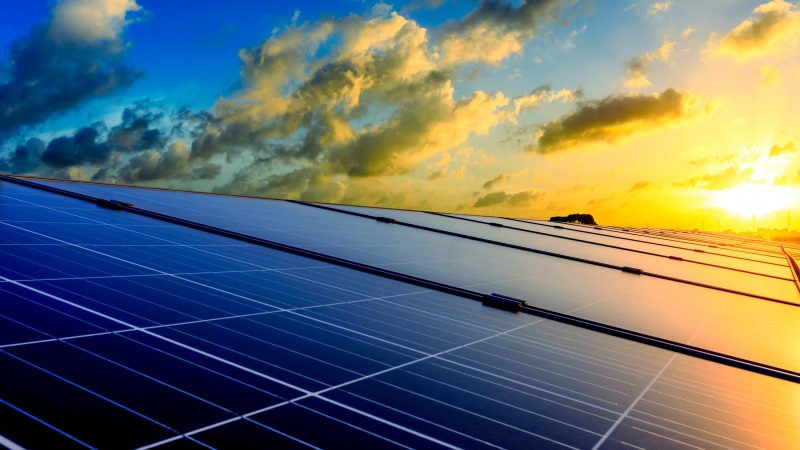 Photovoltaic solar panels and high voltage power lines at sunset sky background,green clean alternative energy.